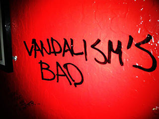 Humorous vandalism on the wall of a bar in San Francisco, reading "VANDALISM'S BAD".